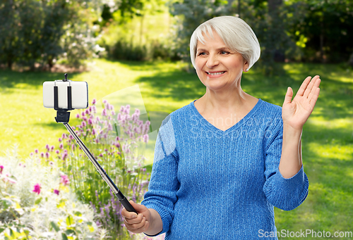 Image of smiling senior woman taking selfie by smartphone