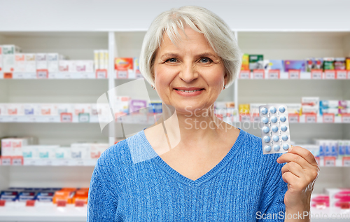 Image of smiling senior woman with pack of pills