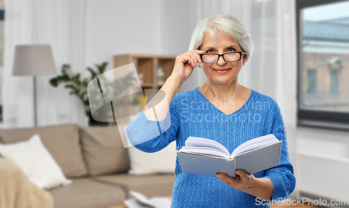 Image of senior woman in glasses reading book