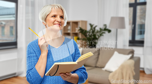 Image of senior woman with pencil and diary or notebook