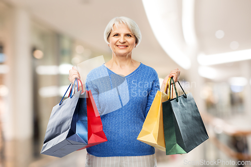 Image of senior woman with shopping bags over grey