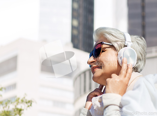 Image of old woman in headphones listens to music in city