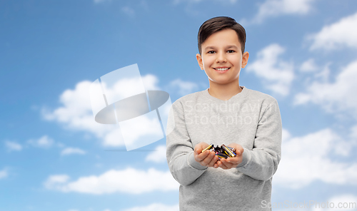 Image of smiling boy holding pile of alkaline batteries