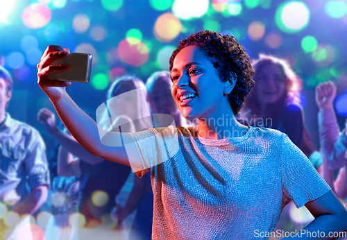 Image of woman taking selfie with smartphone at nightclub