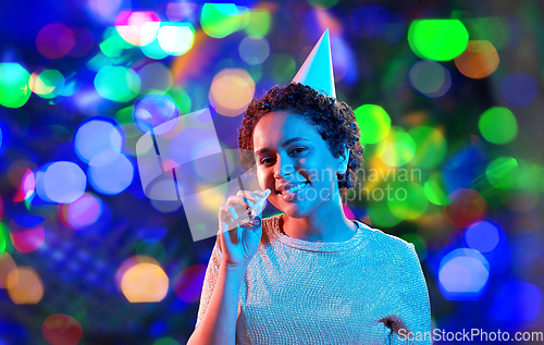 Image of african woman in party cap with blower over black