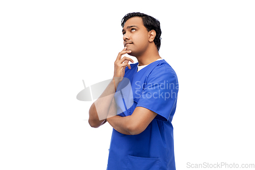 Image of thinking indian male doctor in blue scrubs