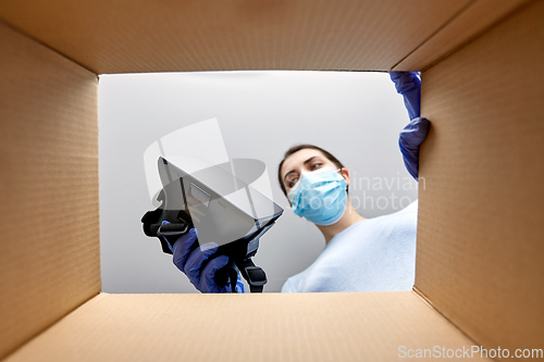 Image of woman in mask taking vr glasses out of parcel box