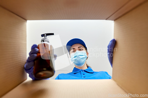 Image of woman in mask packing parcel box with cosmetics