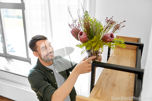 Image of man decorating home with flowers in vase