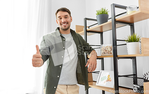 Image of smiling man showing thumbs up at home