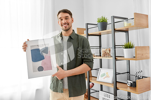 Image of man decorating home with picture in frame