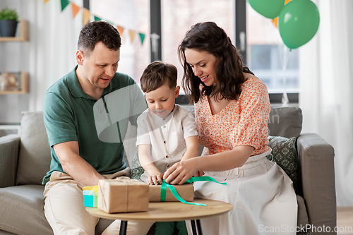 Image of happy family opening birthday presents at home