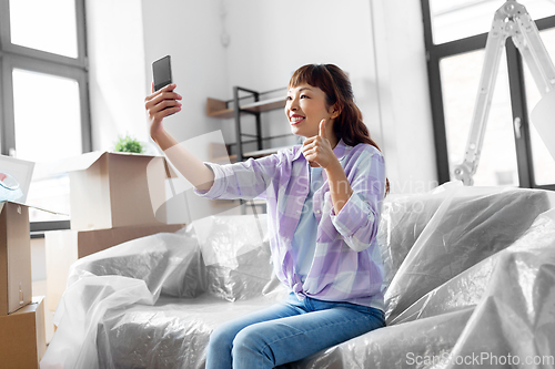 Image of woman with phone having video call at new home