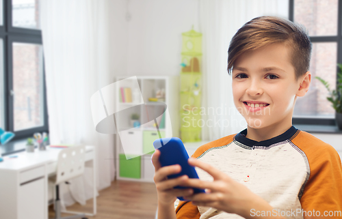 Image of boy with smartphone texting or playing at home