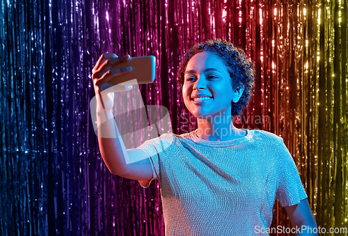 Image of woman taking selfie with smartphone at party