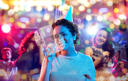 Image of african woman with party blower at nightclub