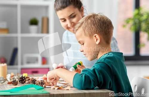 Image of mother and son making pictures of autumn leaves