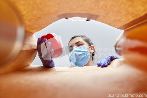 Image of woman in gloves and mask with food in paper bag