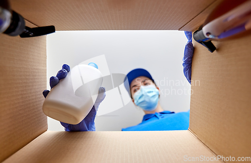 Image of woman in mask packing parcel box with cosmetics