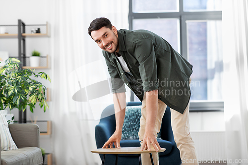 Image of man placing coffee table next to sofa at home