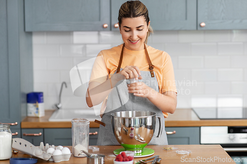 Image of happy young woman cooking food on kitchen at home