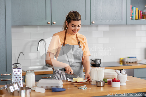 Image of happy young woman cooking food on kitchen at home