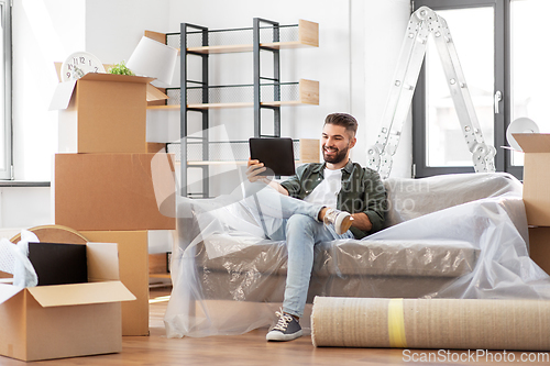 Image of man with tablet pc and boxes moving into new home