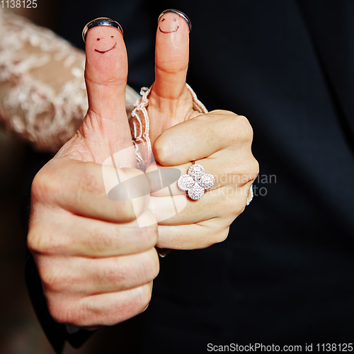 Image of wedding rings on her fingers painted with the bride and groom
