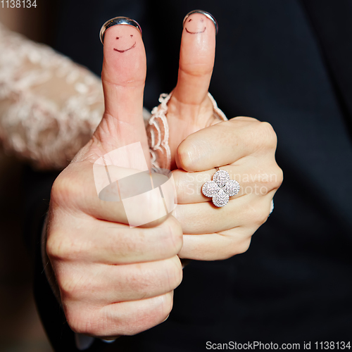 Image of wedding rings on her fingers painted with the bride and groom