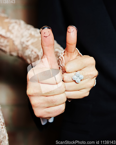 Image of wedding rings on her fingers painted with the bride and groom