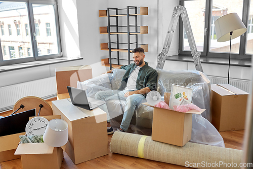 Image of man with laptop computer and moving into new home