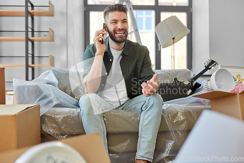 Image of happy man calling on smartphone moving to new home