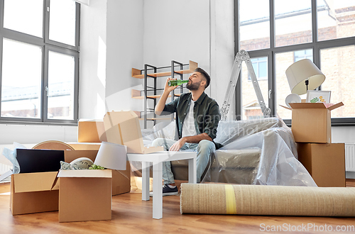 Image of man with box of pizza and beer bottle at new home