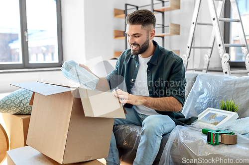 Image of happy man unpacking boxes and moving to new home