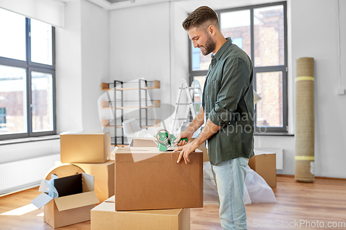 Image of man with adhesive tape packing box at new home