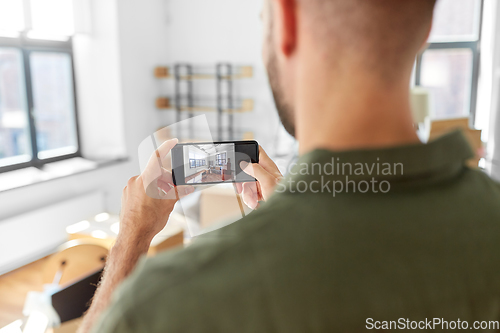 Image of man with smartphone taking picture of new home