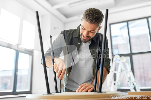 Image of happy man assembling coffee table at new home