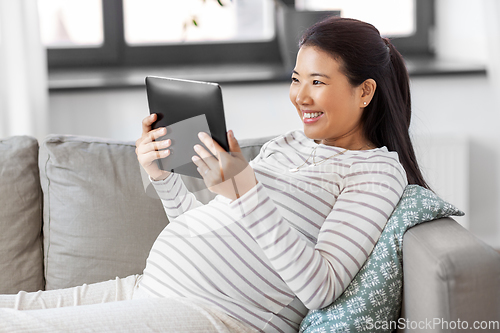 Image of happy pregnant asian woman with tablet pc at home