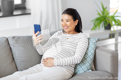 Image of happy pregnant woman with smartphone at home