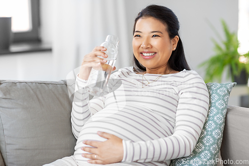 Image of pregnant woman with water in glass bottle at home