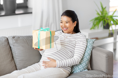 Image of happy pregnant woman with gift box at home