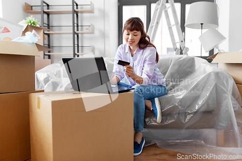 Image of woman with laptop and credit card at new home