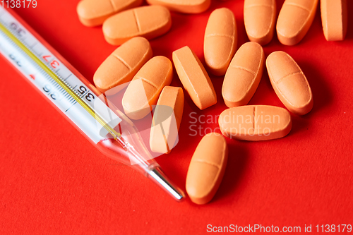 Image of Mercury thermometer and medical pills on background