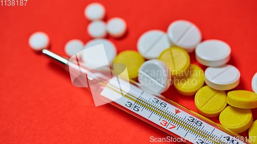 Image of Mercury thermometer and medical pills on background