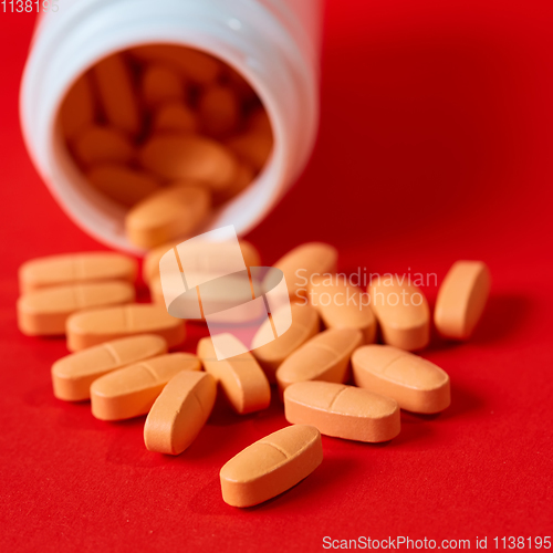 Image of Pills spilling out of pill bottle on red. Top view with copy space. 