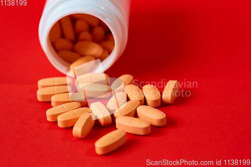 Image of Pills spilling out of pill bottle on red. Top view with copy space. 