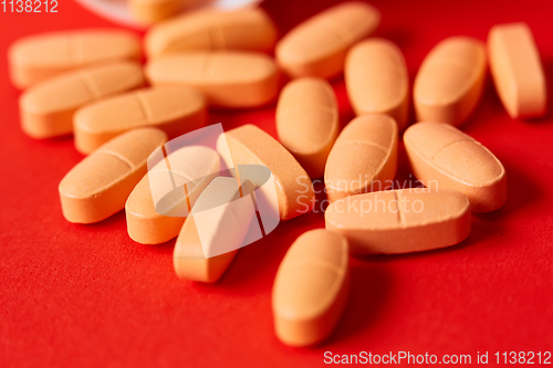 Image of Pills spilling out of pill bottle on red. Top view with copy space. 