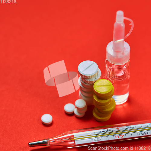 Image of Mercury thermometer and medical pills on background