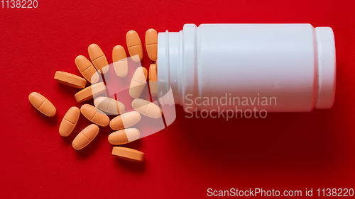 Image of Pills spilling out of pill bottle on red. Top view with copy space. 