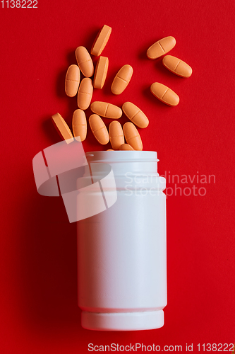 Image of Pills spilling out of pill bottle on red. Top view with copy space. 